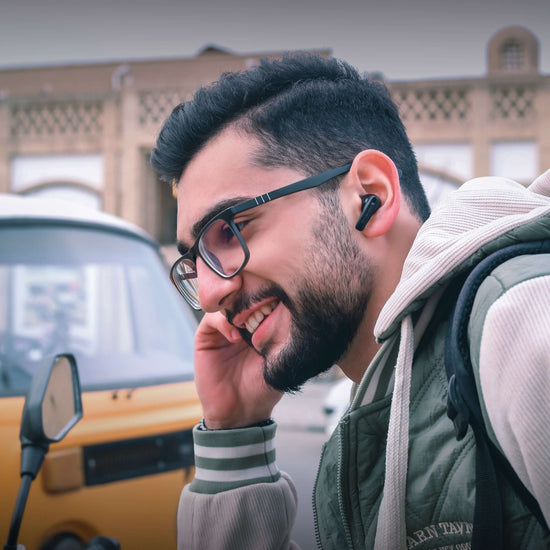 Smiling man wearing Shibela PureSound headphones, enjoying music with a historic backdrop.